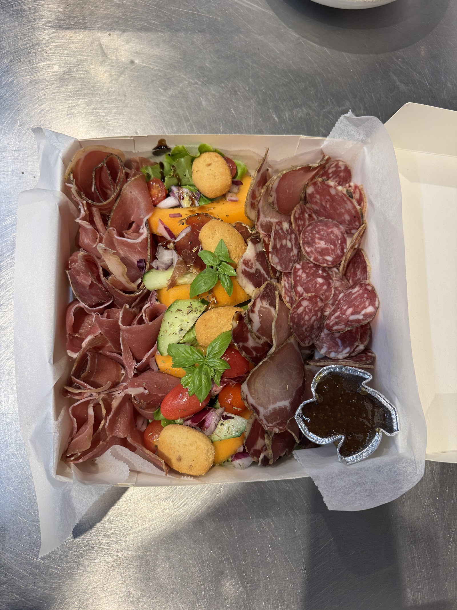 Assiette de charcuterie corse avec melon, tomates cerises et basilic