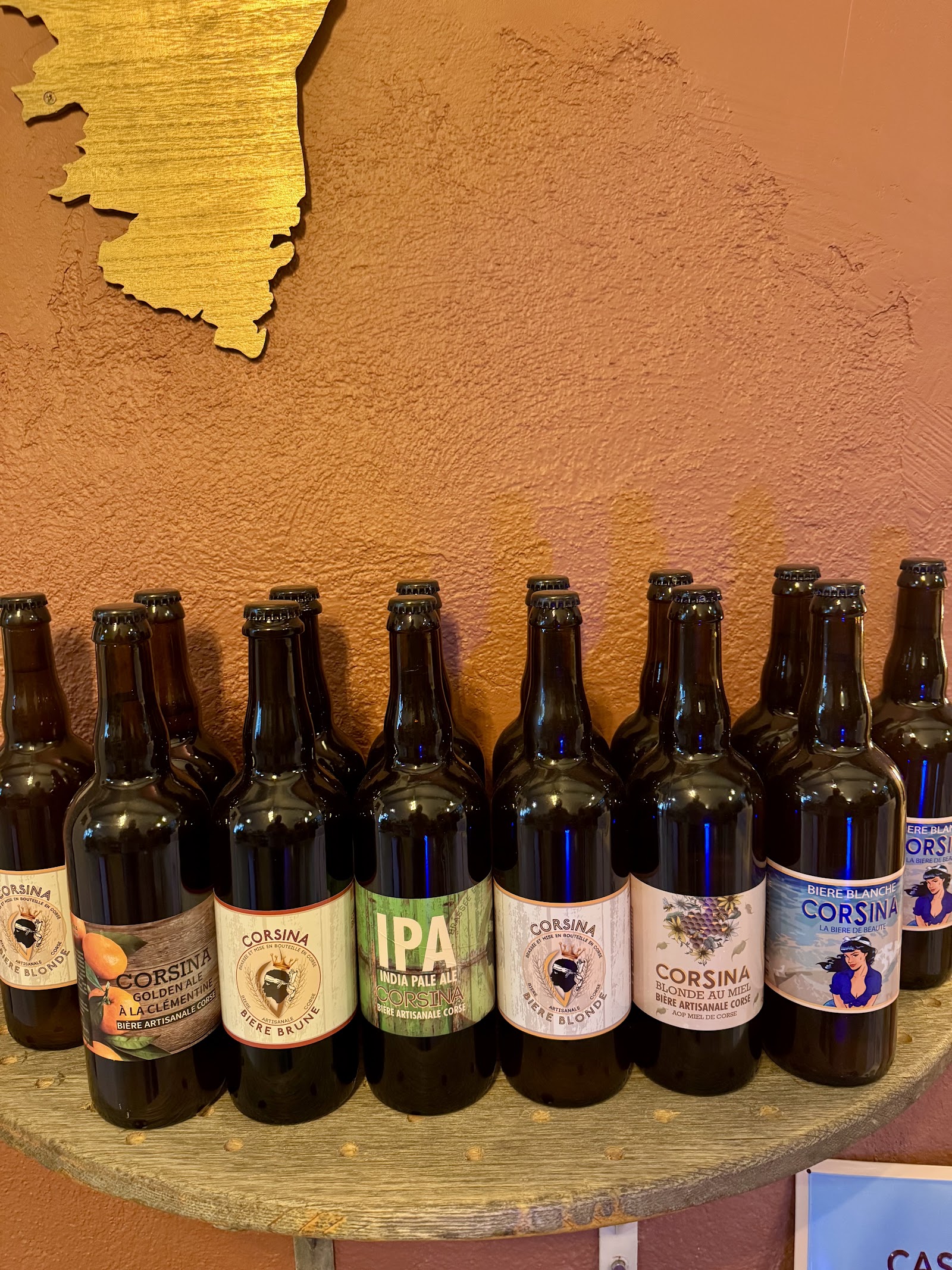 Bières artisanales Corsina alignées sous une carte de la Corse en bois