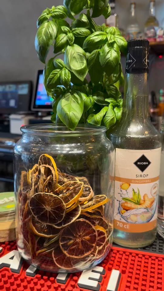 Bocal d'oranges séchées, basilic frais et bouteille de sirop au bar